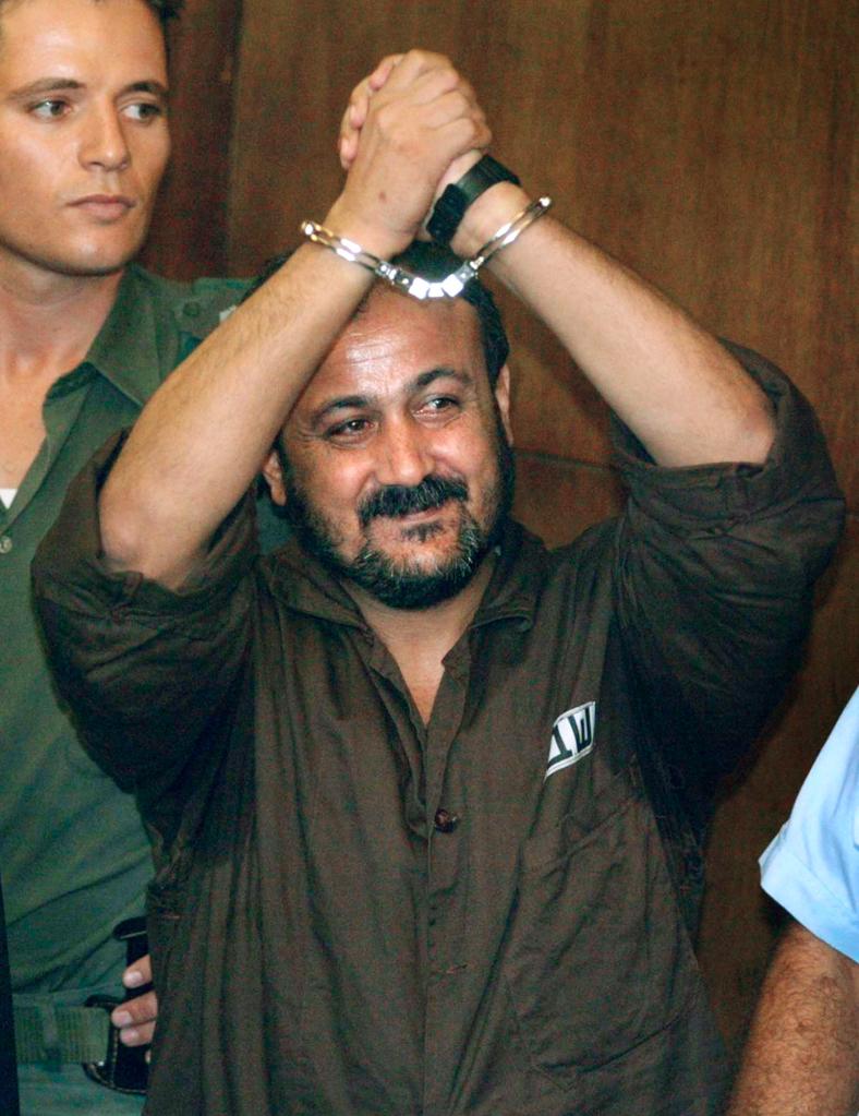 Marwan Barghouti, the West Bank chief of Yasser Arafat's Fatah movement, raising his handcuffed hands on the first day of his trial in Tel Aviv.