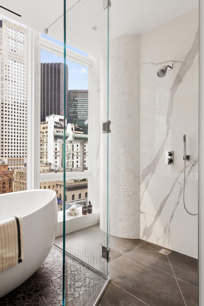 A luxurious marble bathroom with a tub and shower at Baccarat 20 West 53rd Street #18/19C