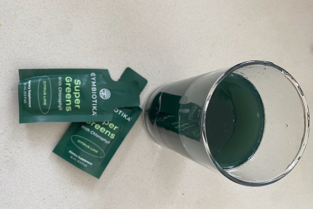 A glass of green liquid next to a packet of green tea