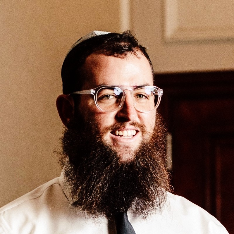 Zvi Kogan smiling in a white shirt and black tie