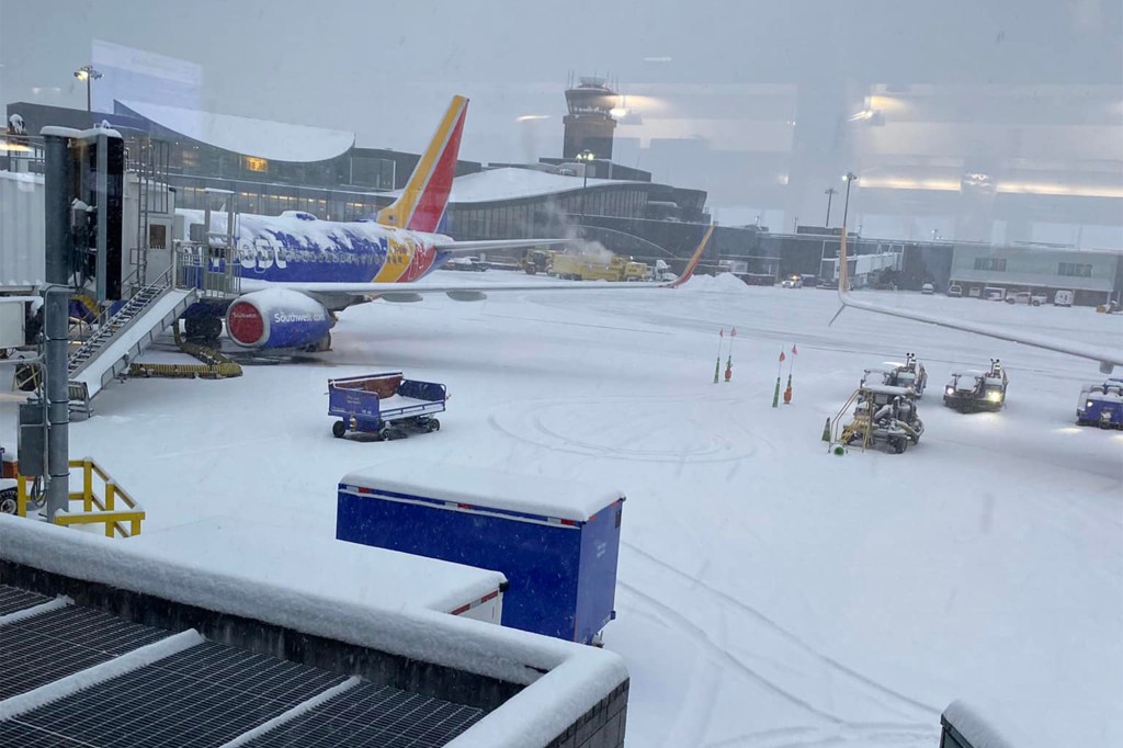 An airplane in the snow during a snowstorm that has resulted in mass flight cancellations and delays across the US