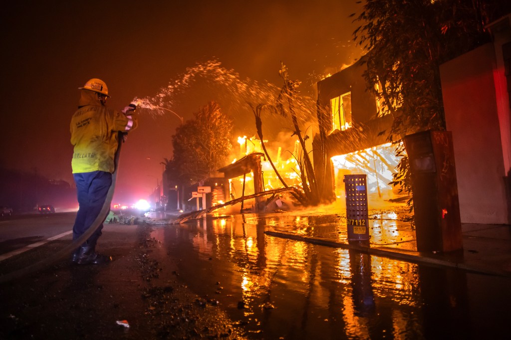 A firefighter sprays water on a burning building.