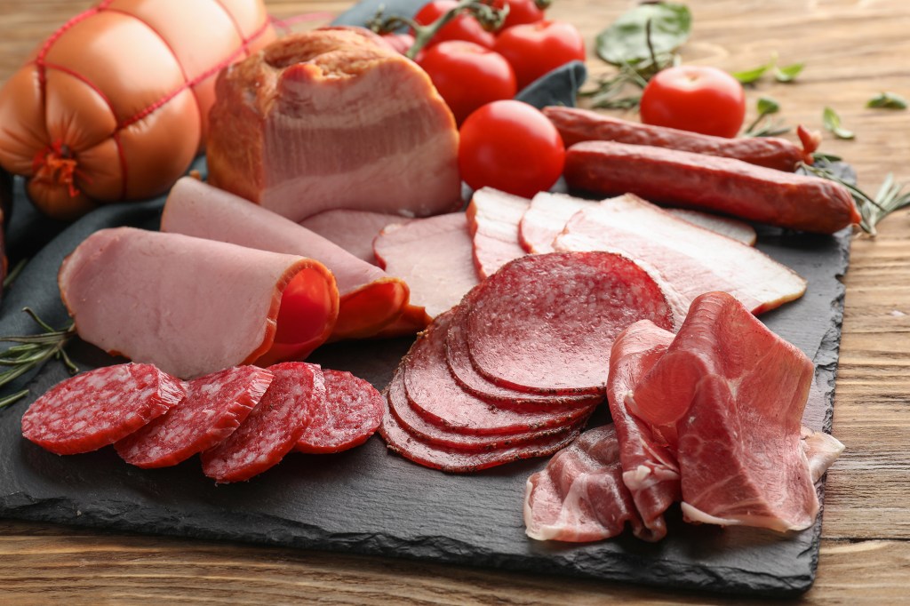 Deli meats, sausages, hot dogs, bacon, corned beef, ham, pepperoni and beef jerky are processed meats. Here, deli meats are shown on a slate plate.