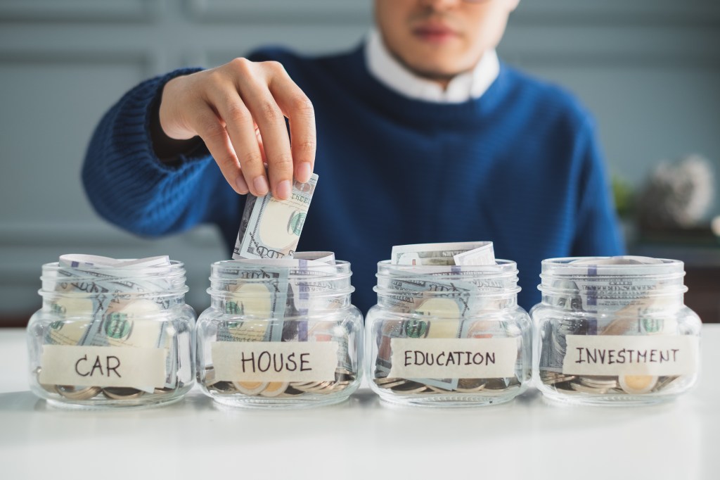 Man placing money into a savings jar for future financial planning