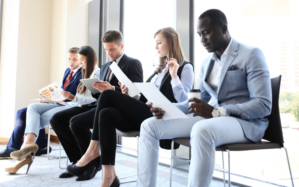 G-Eazy among a group of anxious individuals seated waiting for a job interview