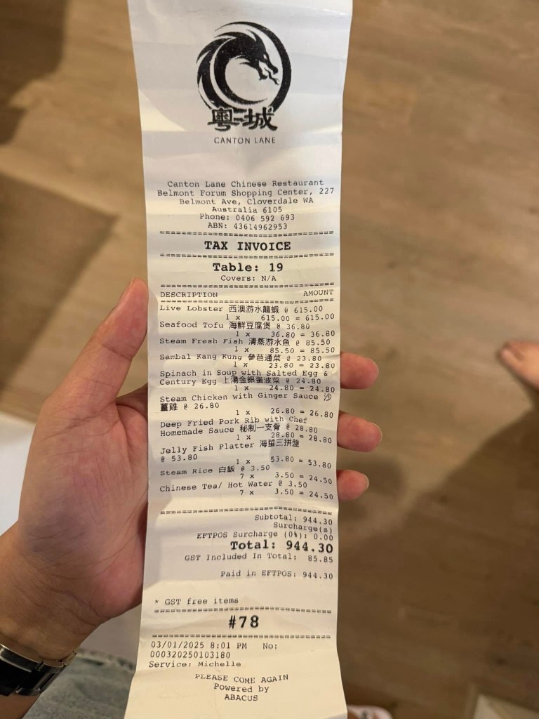 A hand holding a receipt from a Perth restaurant charging $615 for live lobster