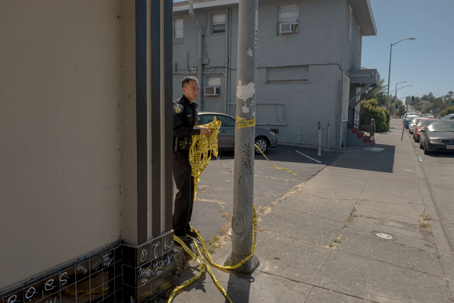 A Vallejo police officer breaks down a crime scene by removing police tape from a pole during daytime.