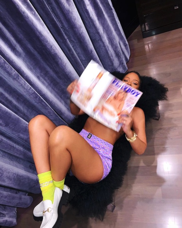 Rihanna posing topless in purple boxers with a copy of Playboy