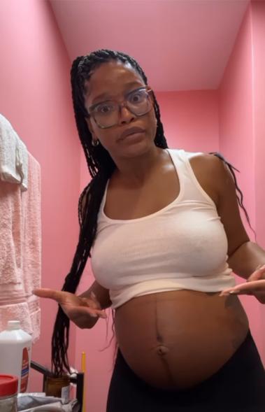 Keke Palmer pointing to her baby bump.