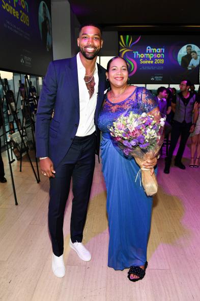 Tristan Thompson stands next to his mother Andrea Thompson as she holds a bouquet of flowers.