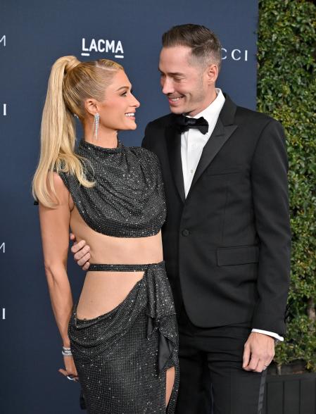 Paris Hilton and Carter Reum smiling at each other on a red carpet.