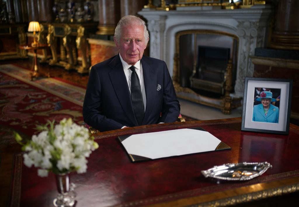 King Charles III sitting at a desk