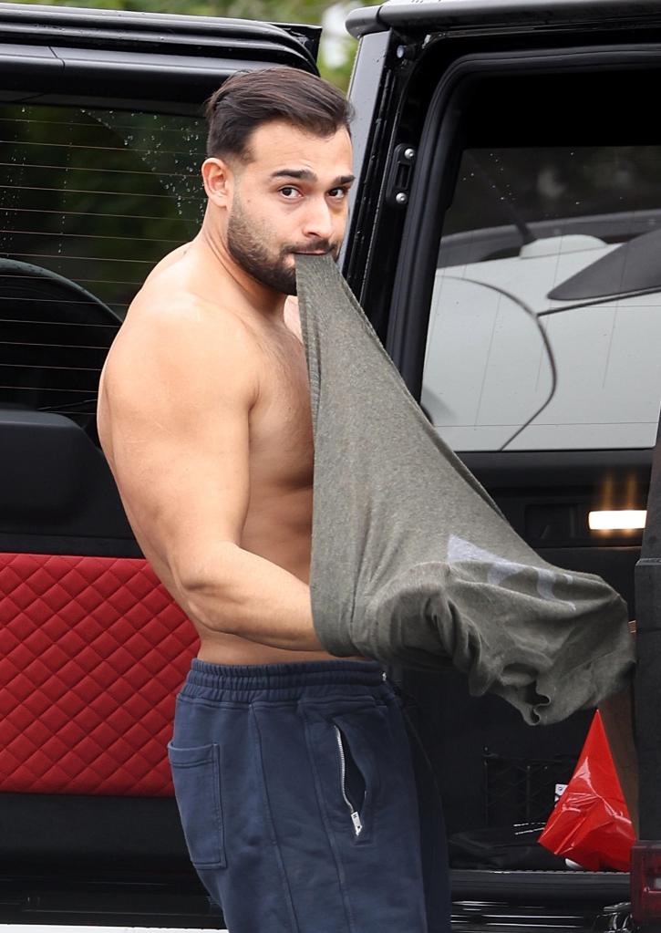 Sam Asghari putting n a shirt.