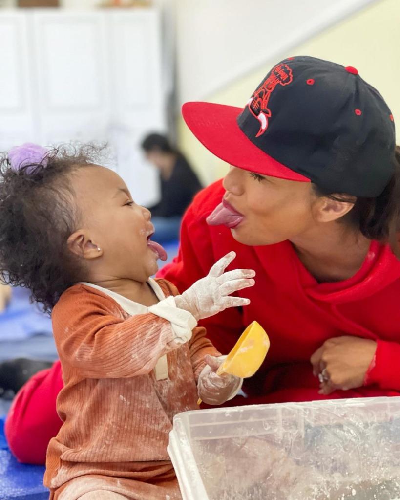 Jeannie Mai in red with daughter Monaco sticking out tongue.