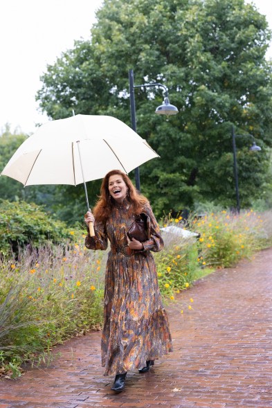 debra messing holding an umbrella and laughing