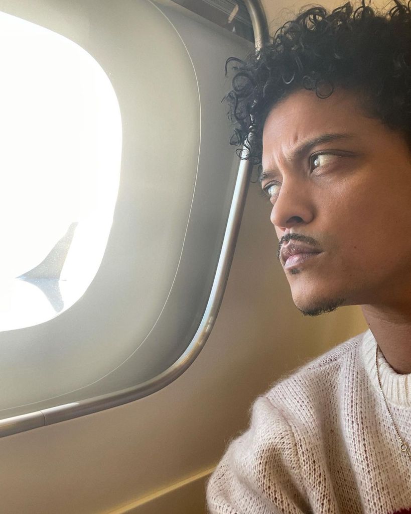 Bruno Mars looking outside of a plane window.