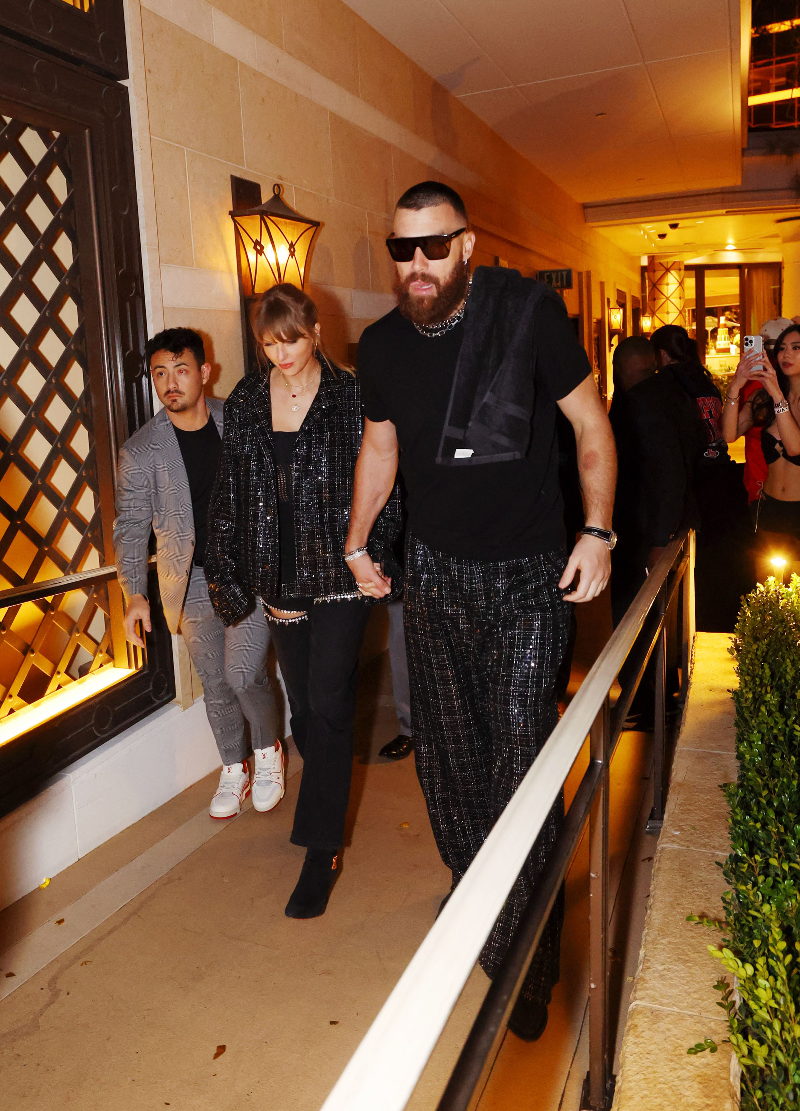 Taylor Swift and Travis Kelce holding hands.