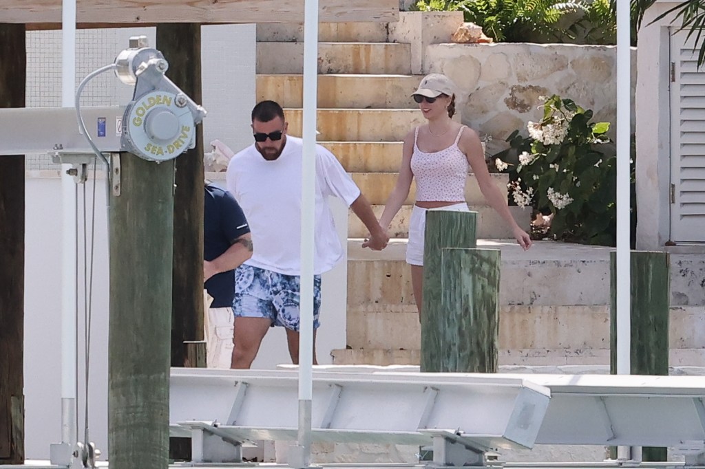 Travis Kelce and Taylor Swift holding hands in the Bahamas. 