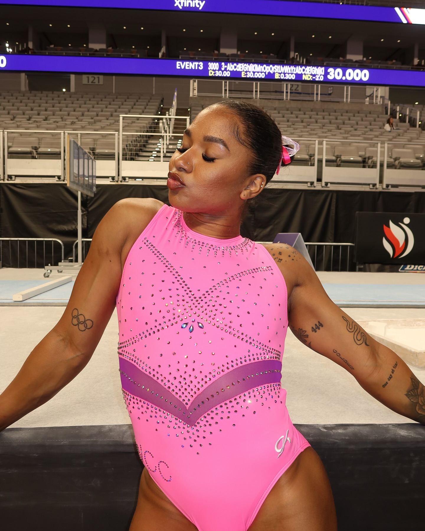 Chiles poses in a pink leotard that shows off her arm tattoos