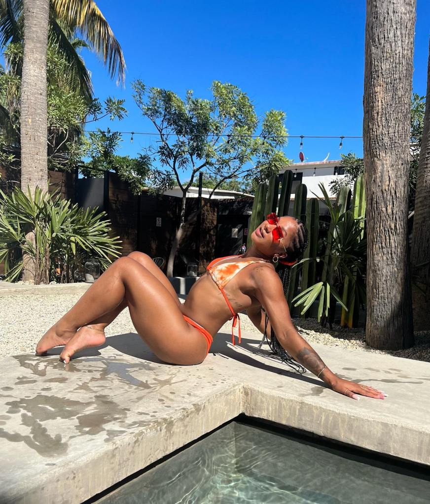 Chiles poses in an orange bikini by the pool with her rose tattoo visible