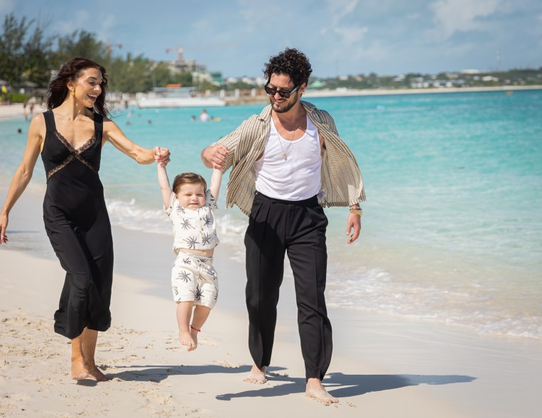 Val Chmerkovskiy and Jenna Johnson swinging their son on the beach