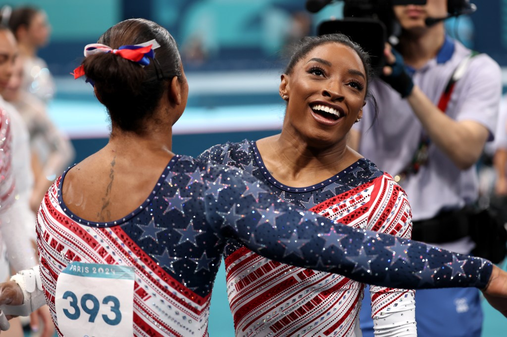 Chiles goes in to hug Biles after she finishes her routine on the uneven bars.