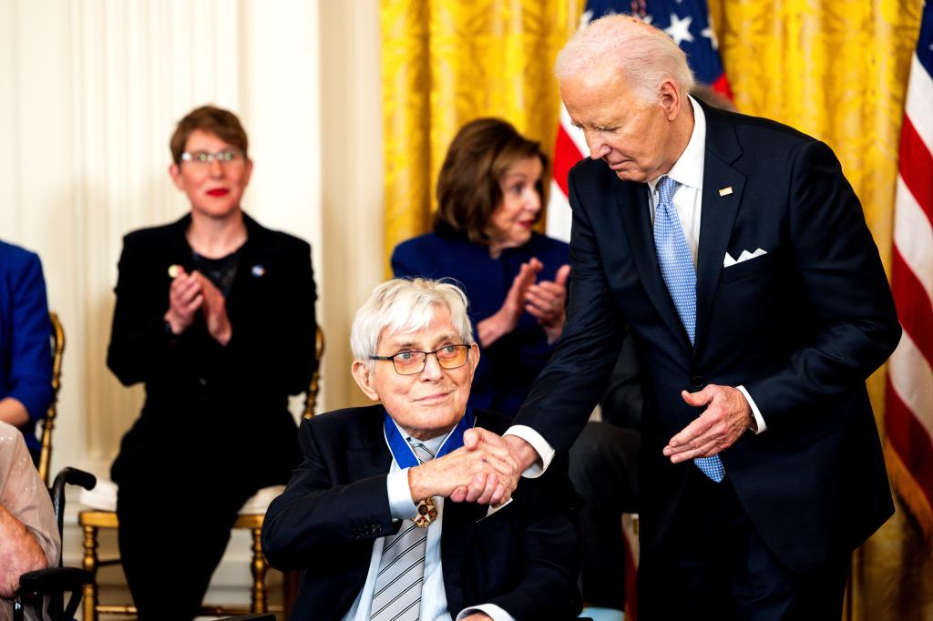 US President Joe Biden, right, shakes hands with journalist Phil Donahue 