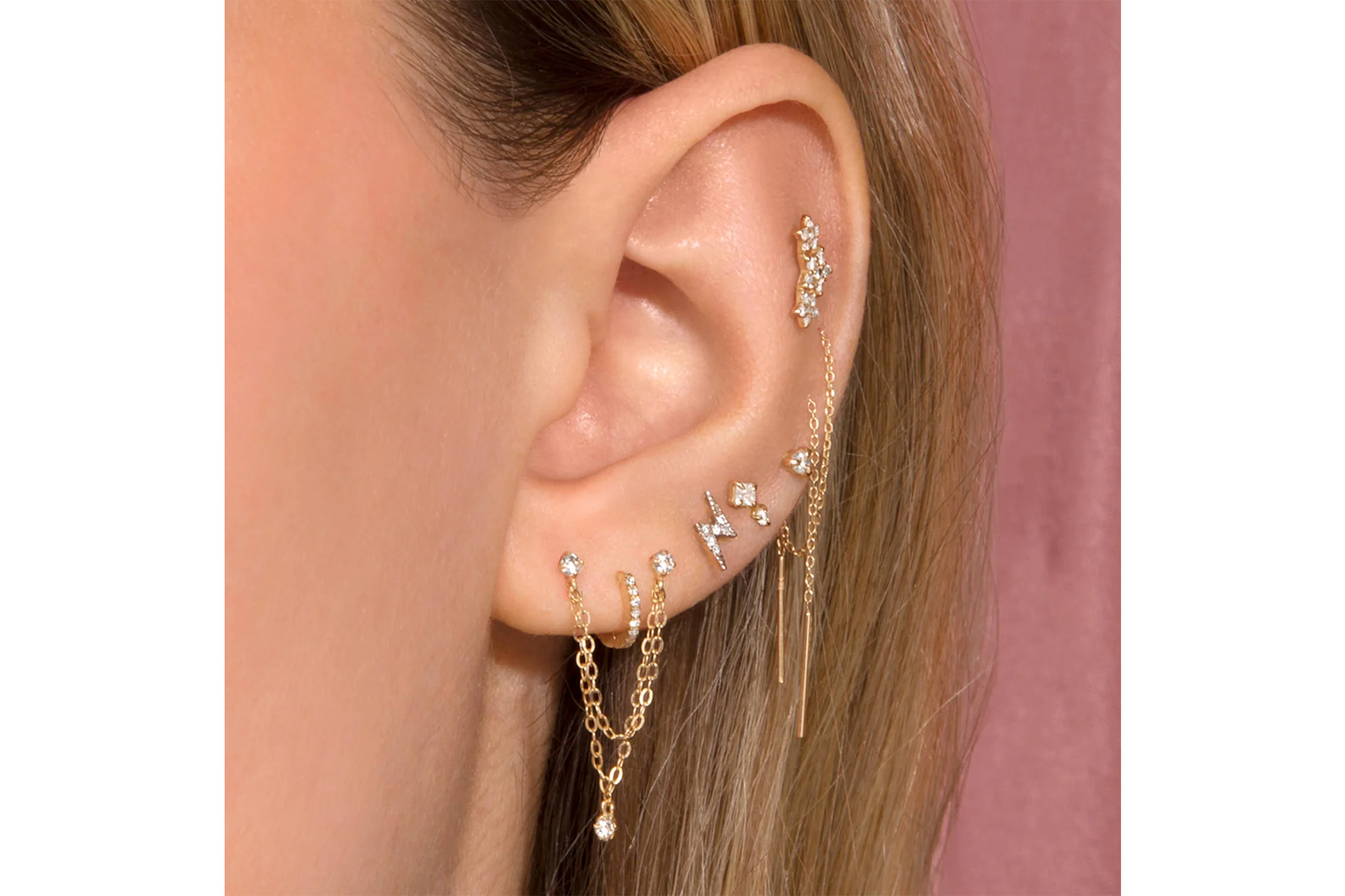 A model's ear with a bunch of earrings on it