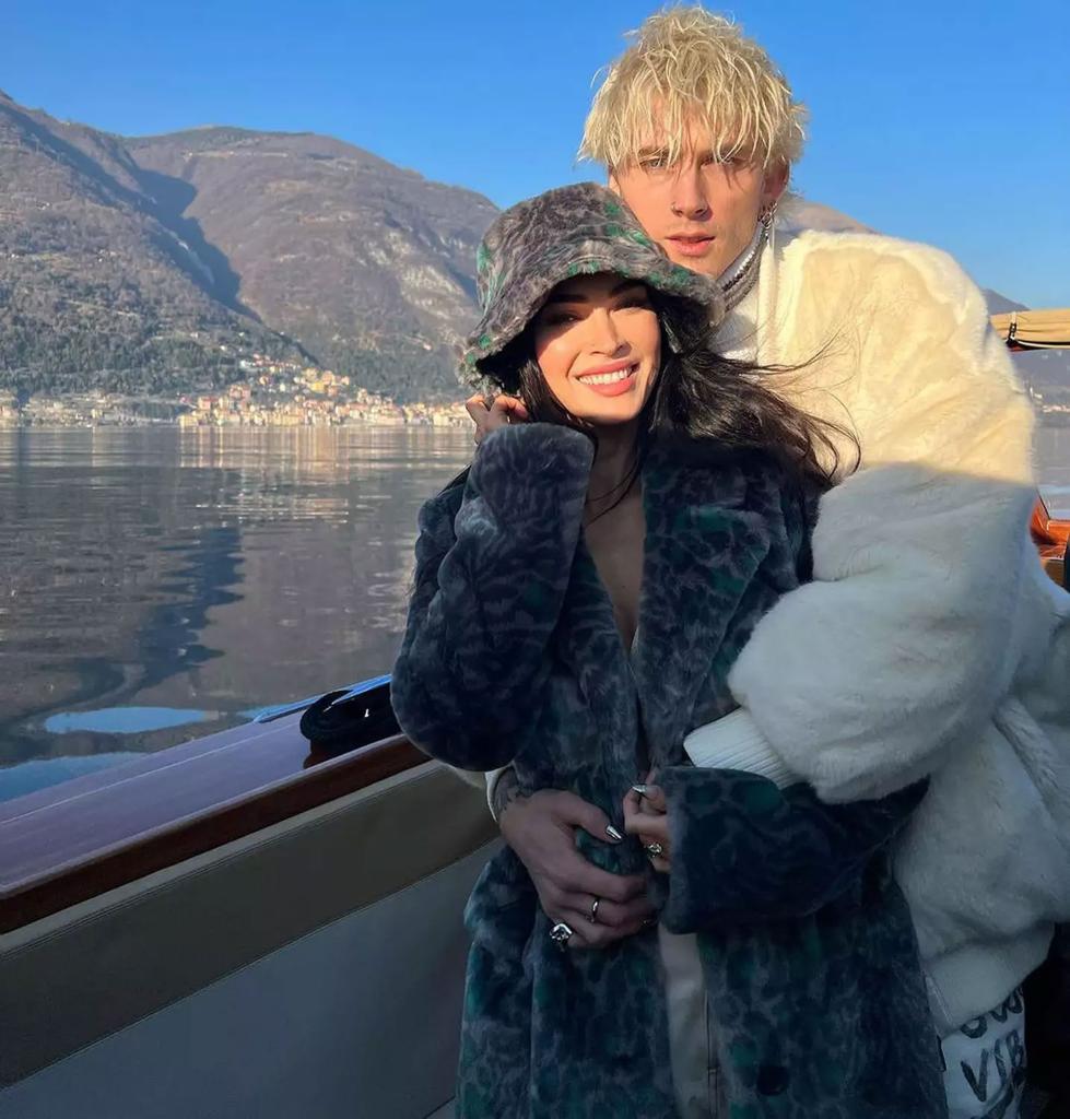 Megan Fox and Machine Gun Kelly pose for a photo in front of a lake.