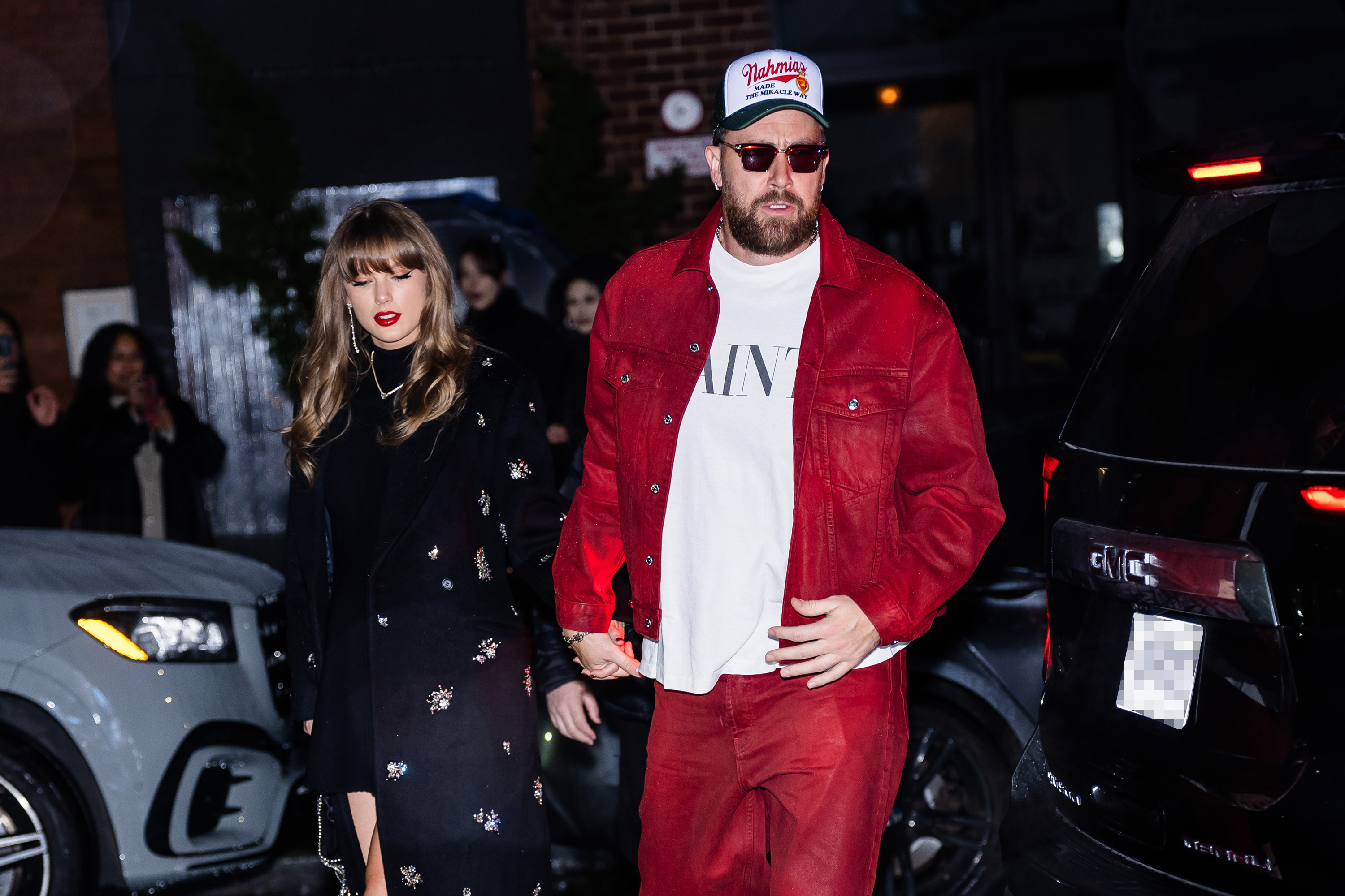 Taylor Swift and Travis Kelce holding hands.