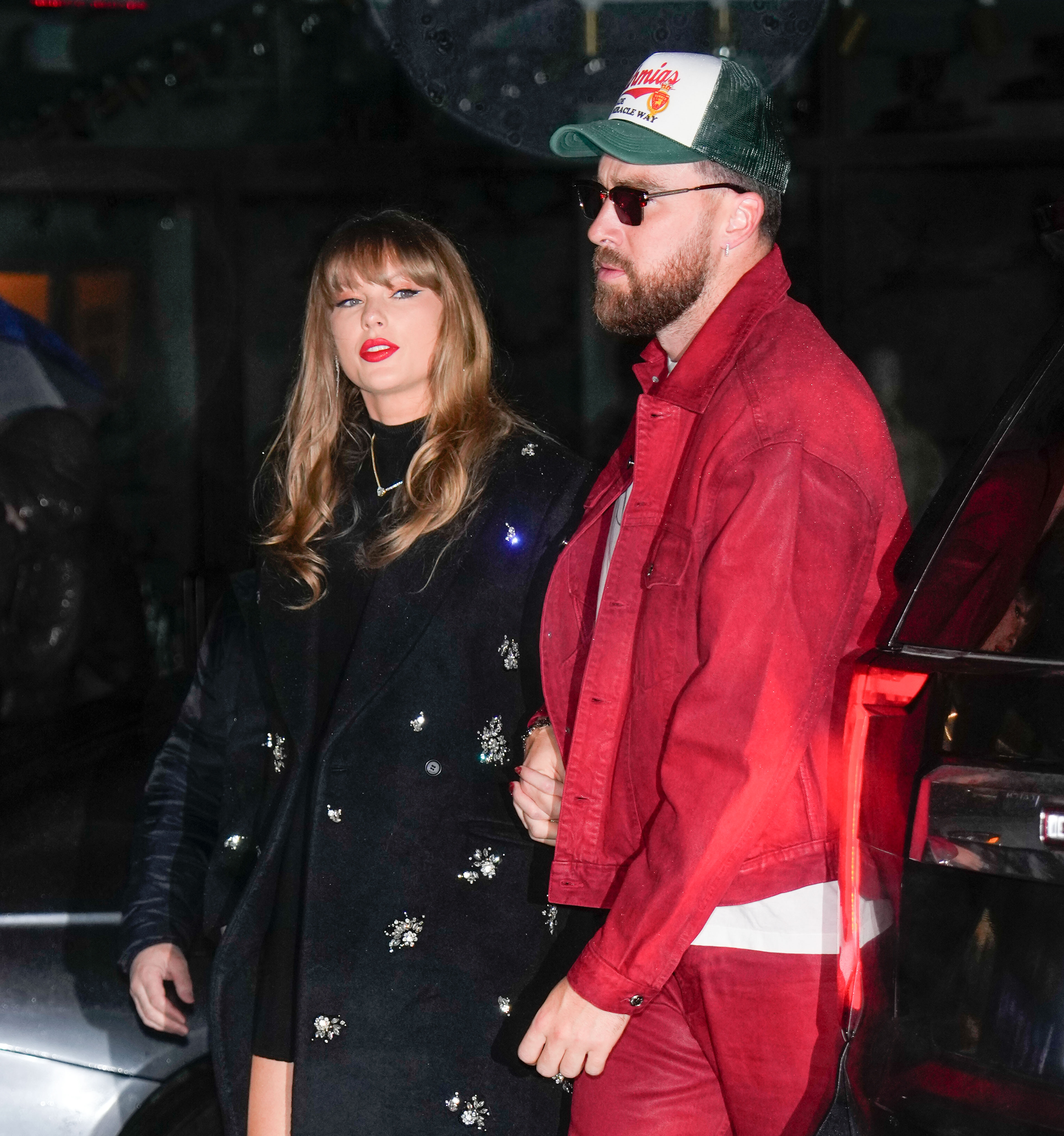 Taylor Swift and Travis Kelce holding hands.