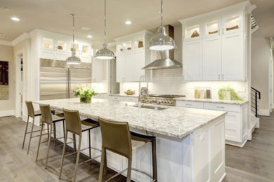 Inspiration for a large modern l-shaped medium tone wood floor, brown floor and vaulted ceiling kitchen pantry remodel in Orlando with an undermount sink, shaker cabinets, white cabinets, granite countertops, white backsplash, subway tile backsplash, stainless steel appliances, an island and multicolored countertops