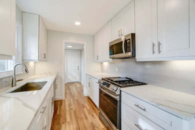 Large trendy light wood floor kitchen photo in DC Metro with an undermount sink, shaker cabinets, white cabinets, quartzite countertops, gray backsplash, subway tile backsplash, stainless steel appliances and white countertops