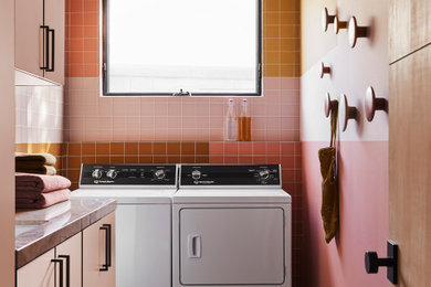 Example of a mid-century modern l-shaped concrete floor and gray floor dedicated laundry room design in Orange County with an undermount sink, flat-panel cabinets, multicolored backsplash, multicolored walls, a side-by-side washer/dryer and gray countertops