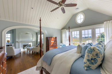 Bedroom - mid-sized coastal master dark wood floor, brown floor and vaulted ceiling bedroom idea in Boston with blue walls, a standard fireplace and a wood fireplace surround