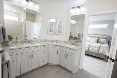 Example of a mid-sized master ceramic tile, brown floor and double-sink bathroom design in Cleveland with recessed-panel cabinets, white cabinets, white walls, an undermount sink, a hinged shower door, multicolored countertops and a built-in vanity
