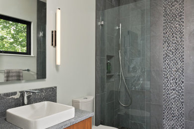 Mid-sized minimalist kids' gray tile and mosaic tile ceramic tile, multicolored floor and single-sink bathroom photo in New York with flat-panel cabinets, medium tone wood cabinets, a one-piece toilet, gray walls, a vessel sink, granite countertops, gray countertops and a floating vanity