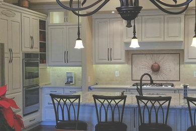 Kitchen - traditional ceramic tile and brown floor kitchen idea in Phoenix with an undermount sink, raised-panel cabinets, beige backsplash, travertine backsplash and stainless steel appliances