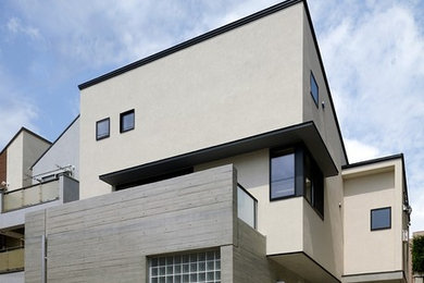 Minimalist beige two-story apartment exterior photo in Tokyo with a shed roof, a metal roof and a black roof