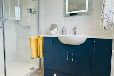 Design ideas for a medium sized modern family bathroom in Other with flat-panel cabinets, blue cabinets, a corner shower, a one-piece toilet, white tiles, ceramic tiles, white walls, vinyl flooring, a built-in sink, quartz worktops, brown floors, a hinged door, white worktops, a single sink and a built in vanity unit.