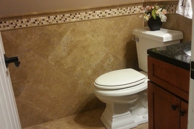Small trendy beige tile and stone tile travertine floor bathroom photo in Columbus with raised-panel cabinets, medium tone wood cabinets, granite countertops, a two-piece toilet and brown walls