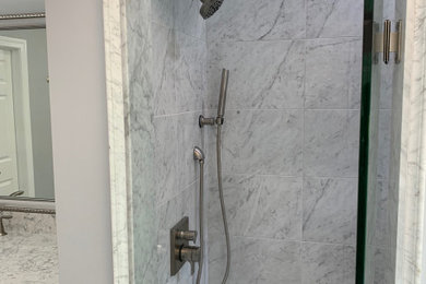 Large elegant master gray tile, white tile and marble tile porcelain tile and gray floor bathroom photo in Other with raised-panel cabinets, white cabinets, gray walls, an undermount sink, marble countertops, a hinged shower door and gray countertops