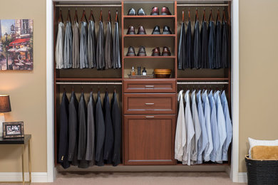Example of a small trendy gender-neutral carpeted reach-in closet design in Boston with raised-panel cabinets and dark wood cabinets