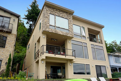 Example of a large minimalist brown three-story stucco exterior home design in Seattle