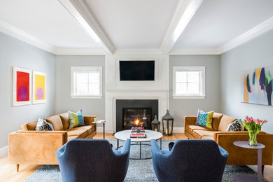 Inspiration for a transitional light wood floor family room remodel in Boston with gray walls, a standard fireplace and a wall-mounted tv