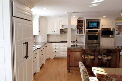 ボストンにあるトランジショナルスタイルのおしゃれなキッチン (アンダーカウンターシンク、レイズドパネル扉のキャビネット、白いキャビネット、御影石カウンター、白いキッチンパネル、セラミックタイルのキッチンパネル、シルバーの調理設備、淡色無垢フローリング) の写真