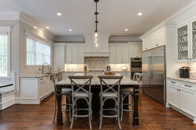 Open concept kitchen - large transitional u-shaped medium tone wood floor and brown floor open concept kitchen idea in Raleigh with a farmhouse sink, recessed-panel cabinets, white cabinets, granite countertops, white backsplash, stainless steel appliances, an island and white countertops
