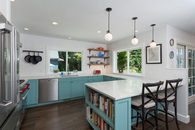 Inspiration for a mid-sized modern brown floor eat-in kitchen remodel in Seattle with a farmhouse sink, blue cabinets, quartzite countertops, white backsplash, subway tile backsplash, stainless steel appliances, a peninsula and white countertops