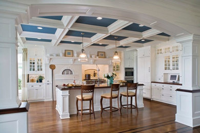 Eat-in kitchen - large traditional u-shaped medium tone wood floor eat-in kitchen idea in Boston with raised-panel cabinets, white cabinets, wood countertops, white backsplash, stainless steel appliances, an island, a double-bowl sink and ceramic backsplash