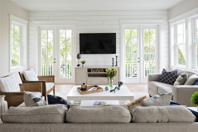 Example of a large beach style open concept light wood floor, beige floor and shiplap wall living room design in Tampa with white walls and a wall-mounted tv